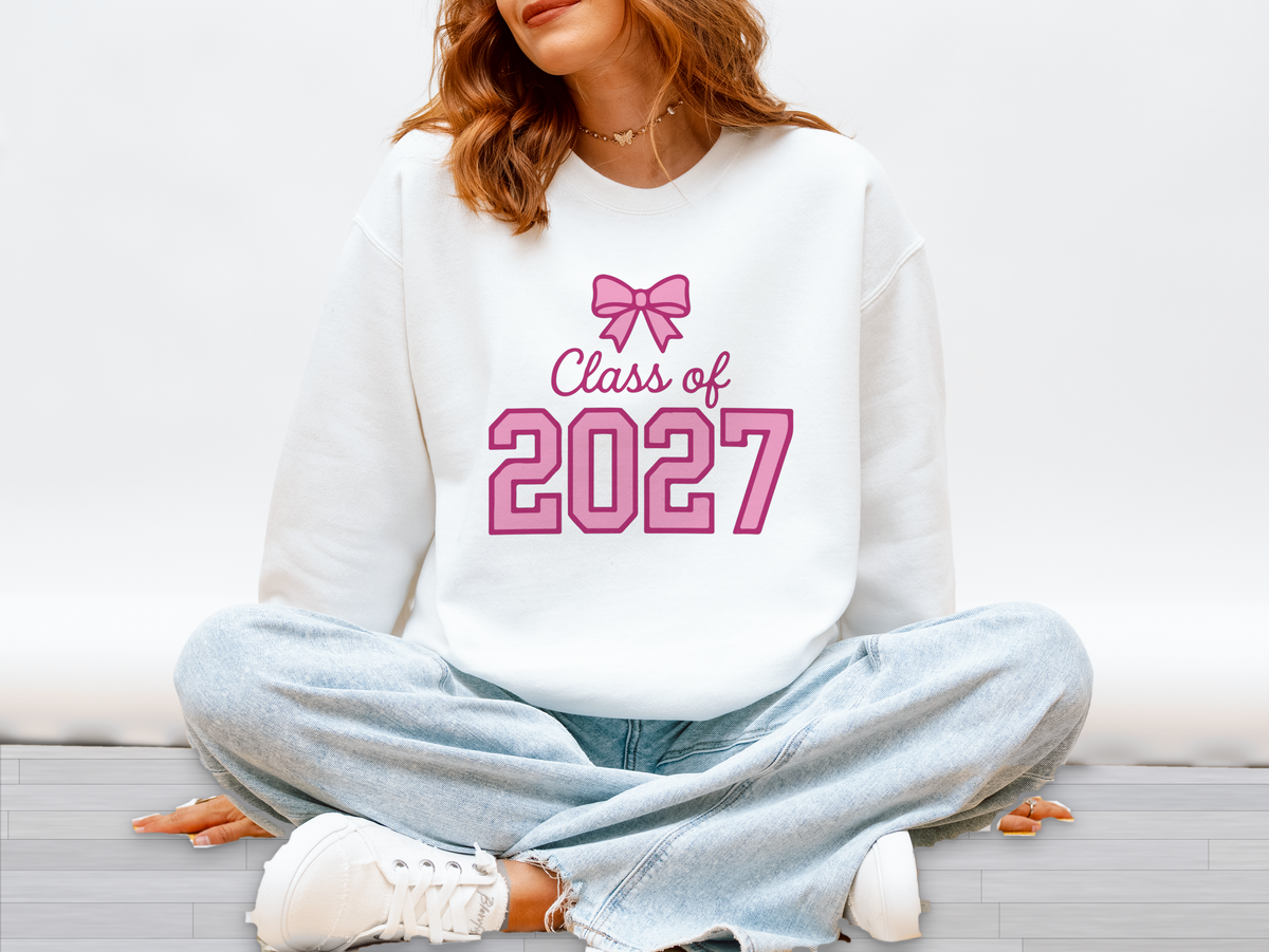Woman wearing a white sweatshirt with Class of 2027 in pink and a pink bow