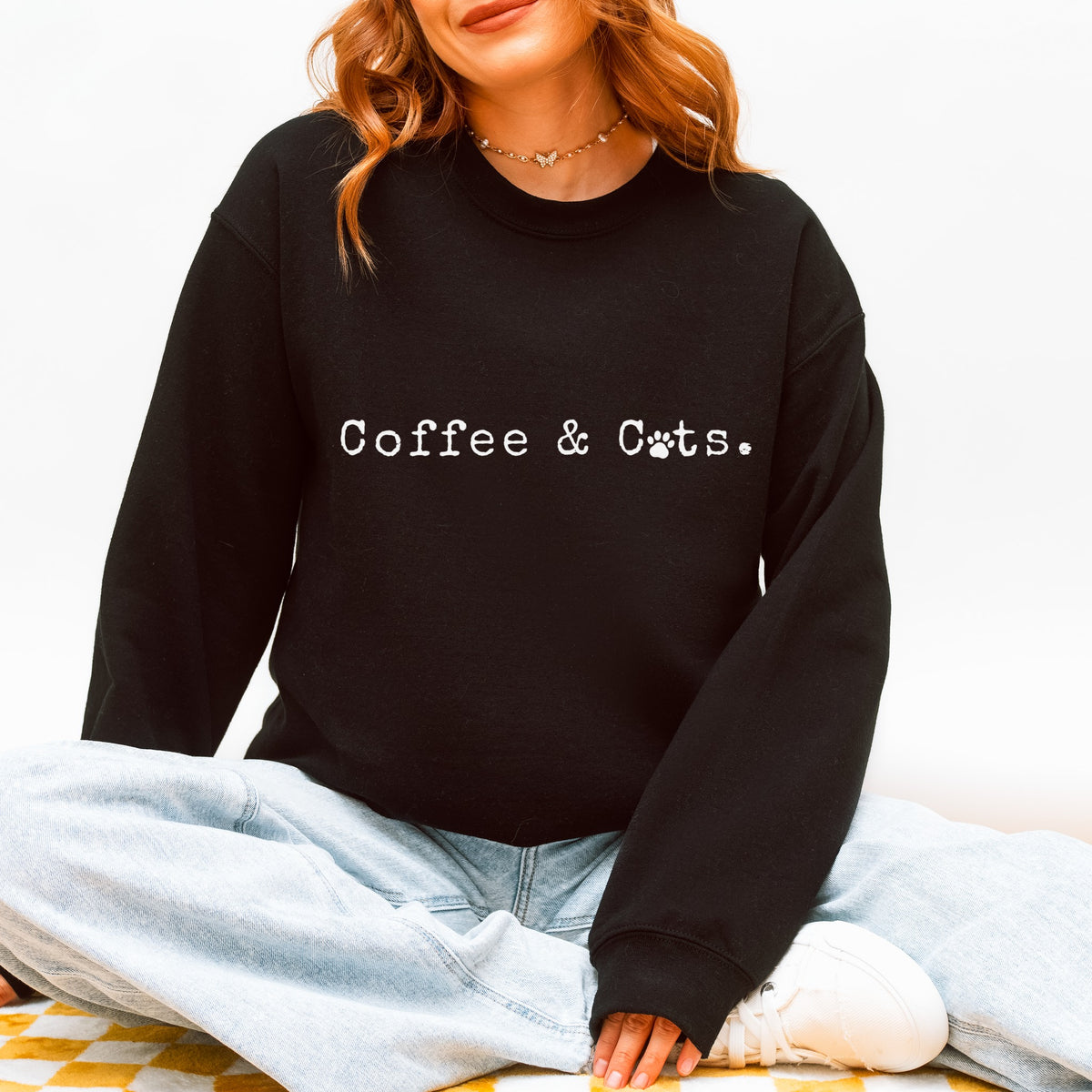 Woman wearing a black crewneck sweatshirt that reads Coffee & Cats