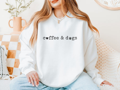 Woman wearing a white crewneck sweatshirt that reads coffee & dogs