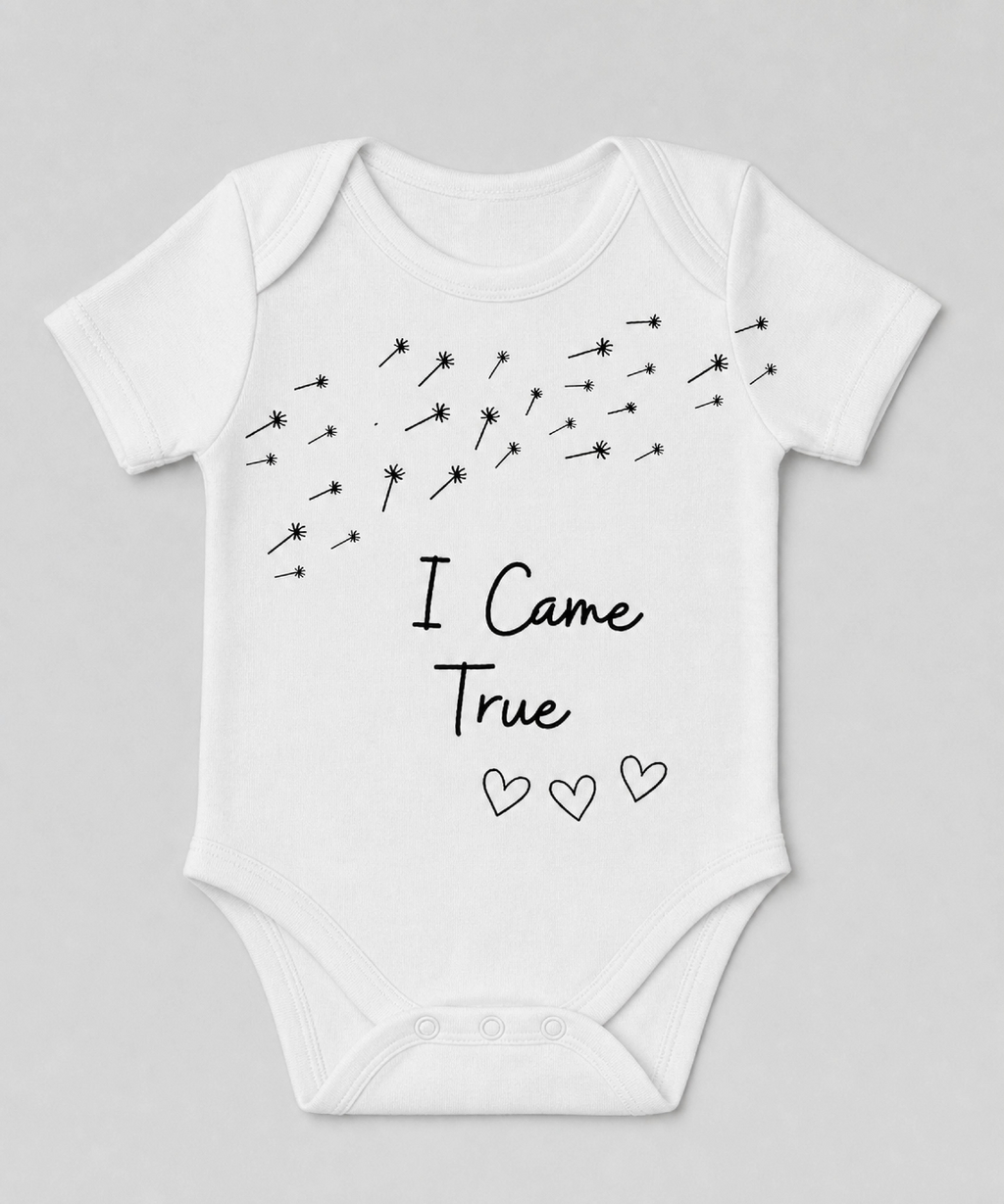 White baby onesie with dandelion seeds and the words I Came True