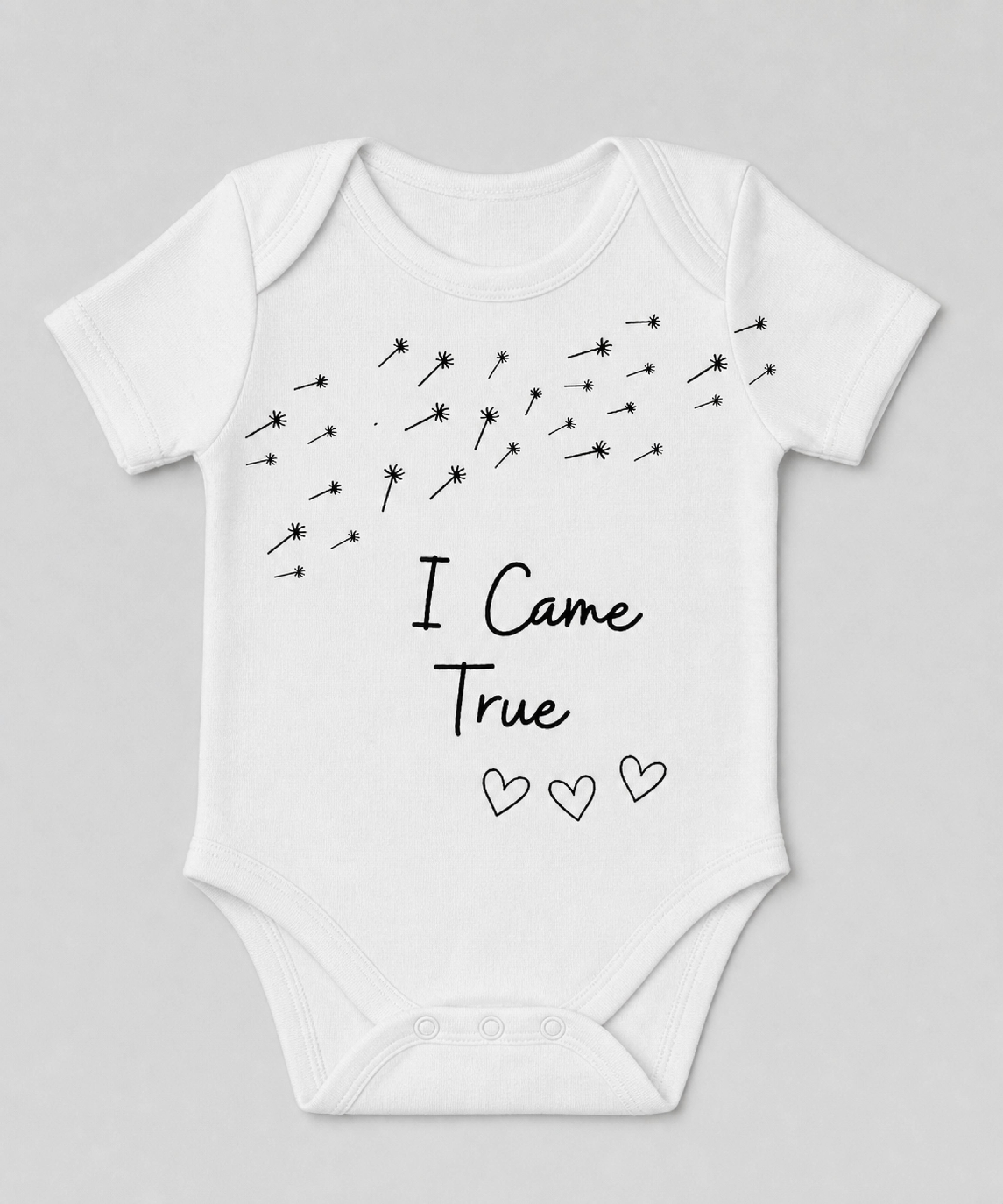White baby onesie with dandelion seeds and the words I Came True