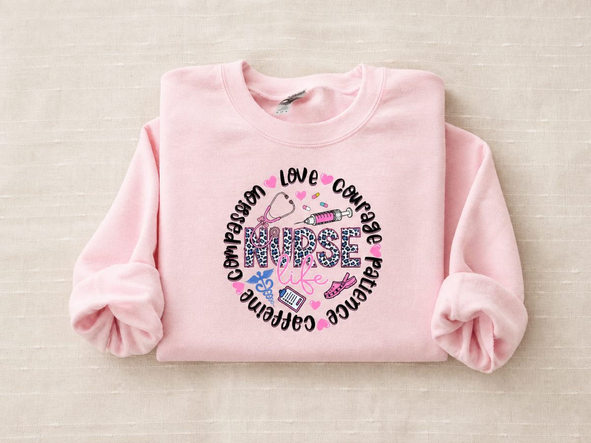 Pink crewneck sweatshirt with a circular nurse life design reading compassion, love, courage, patience, caffeine