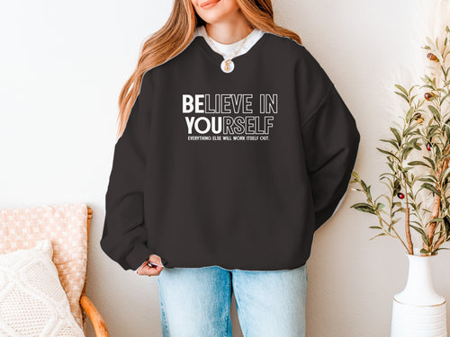 Woman wearing a black crewneck sweatshirt that reads Believe In Yourself with Be You highlighted
